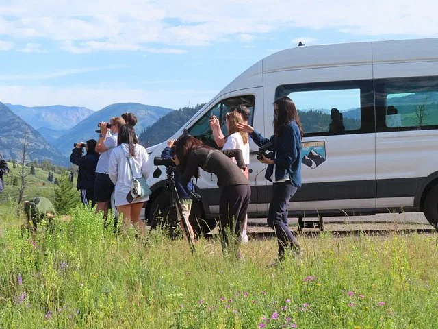 A group of people taking photos near a white tour van