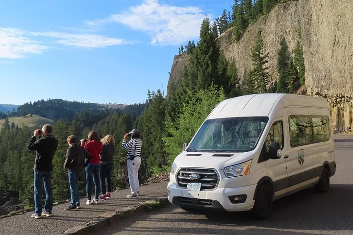 Tourists looking out over a canyon from a scenic viewpoint next to a van
